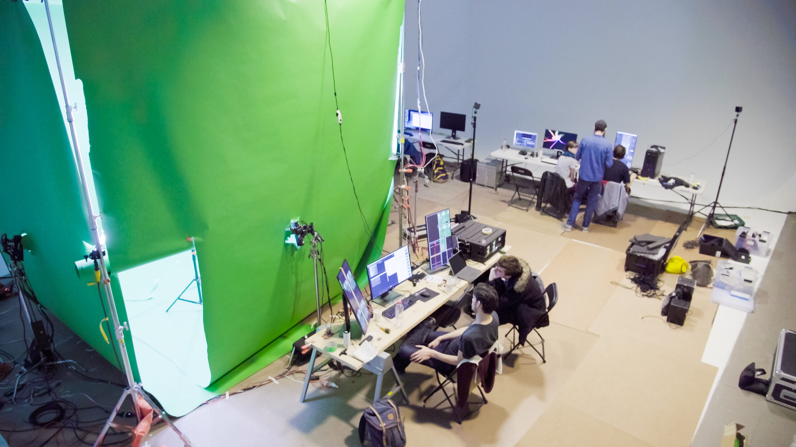 Overhead production view shows performers, green screens, cameras, and workstations on the volumetric capture stage.