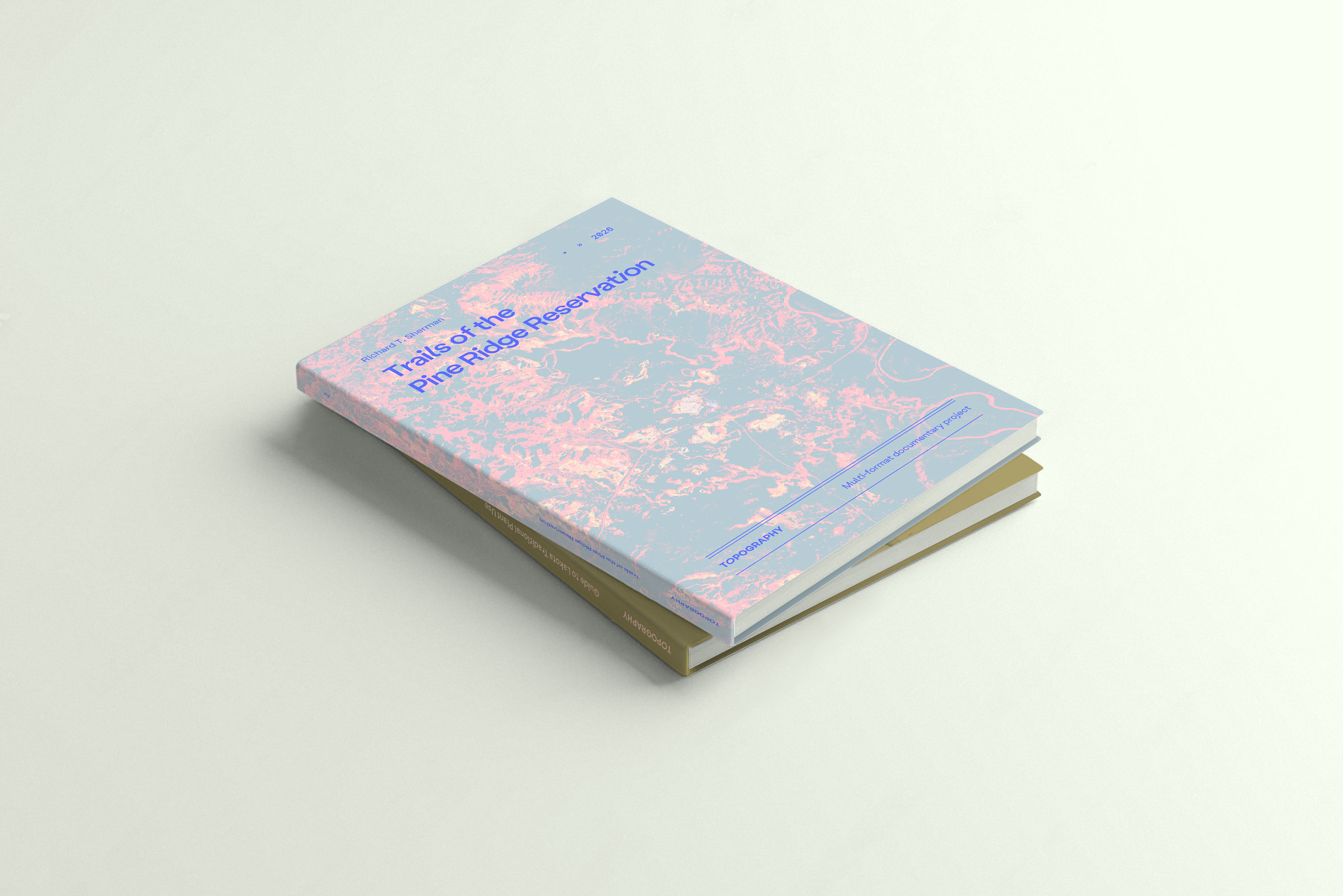 A square publication prototype with an iridescent topographic cover rests on a pale surface.
