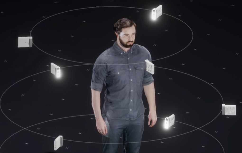 A performer stands inside a circular array of depth cameras in a dark capture studio.