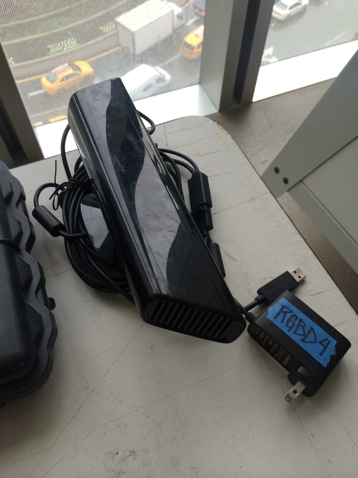 A first-generation Kinect depth sensor and labeled power adapter on the Camera of the Future workshop table.